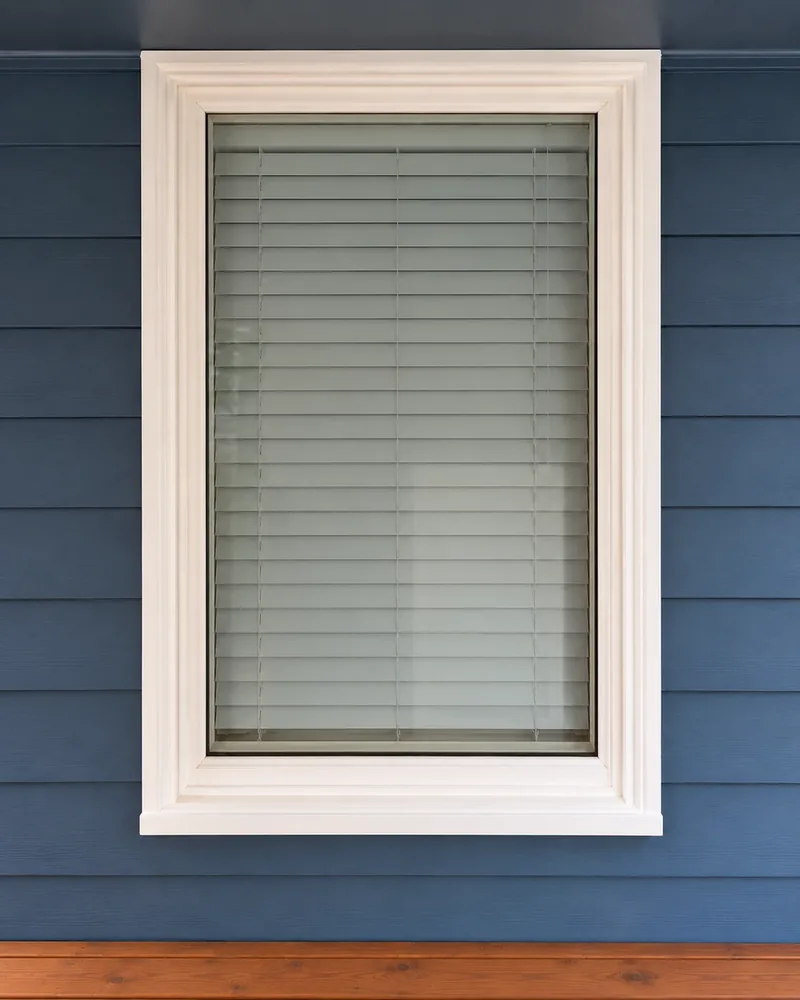 Window with white trim set in blue lap siding